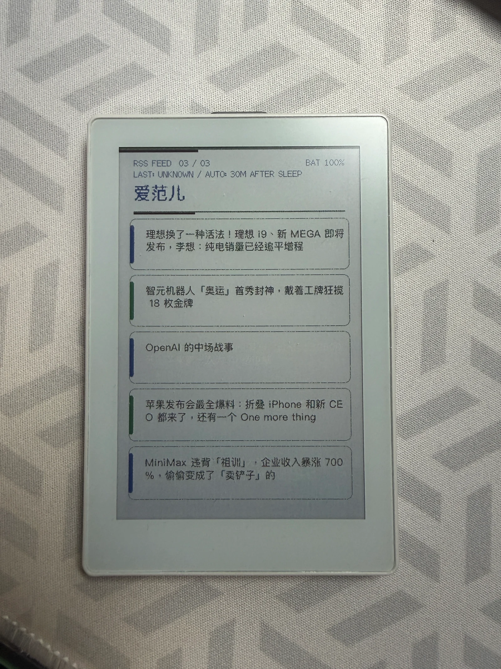 PaperColor 正面实拍:爱范儿订阅源下的五条中文新闻,顶部显示电量与更新状态。